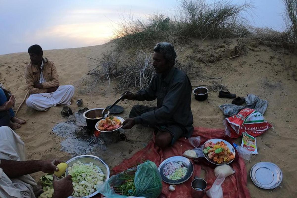 un gruppo di persone sedute sulla spiaggia che mangiano cibo