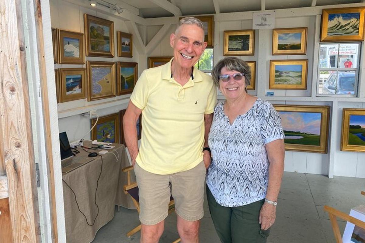 a man and a woman standing in a room with paintings