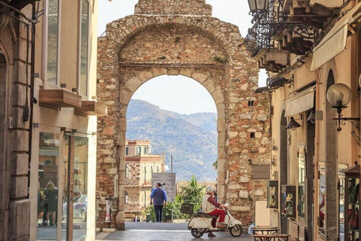 una persona che guida uno scooter sotto un arco in una strada