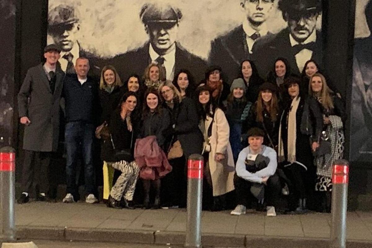 um grupo de pessoas em pé em frente a um mural