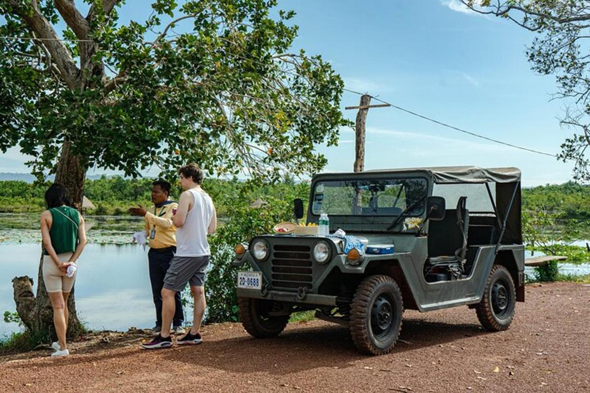 eine Gruppe von Menschen steht um einen grünen Jeep herum