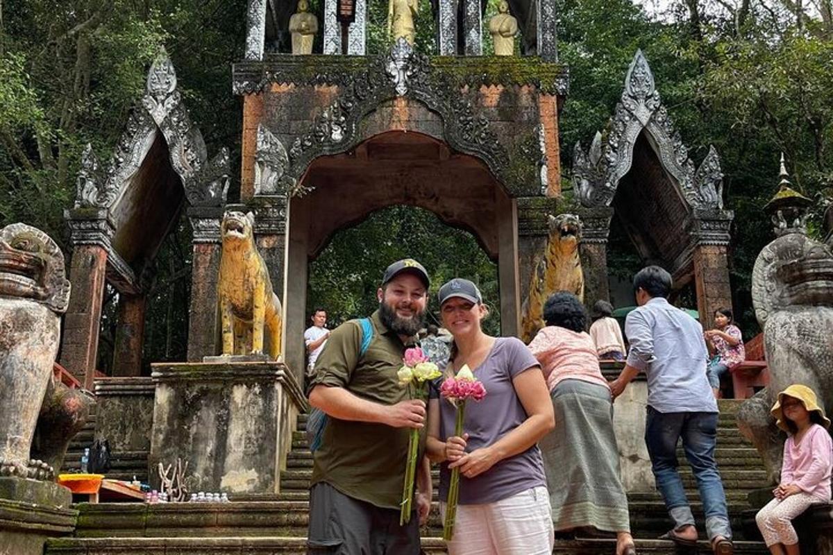 ein Mann und eine Frau halten Blumen vor einem Tempel