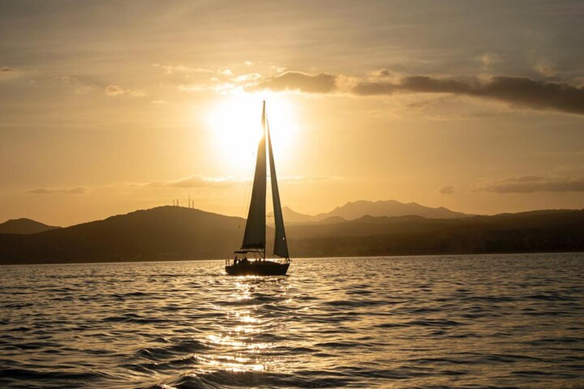 una barca a vela in acqua con il sole che tramonta