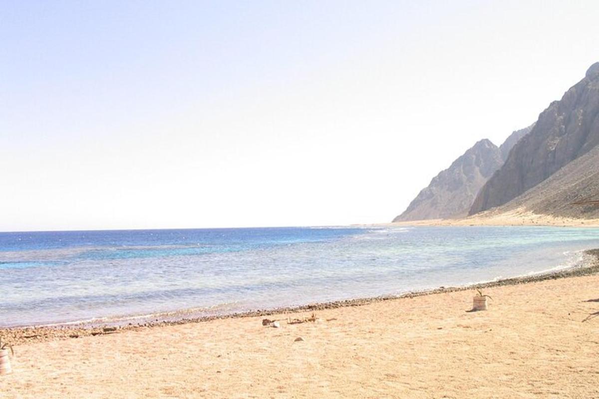 a beach with the ocean and mountains in the background