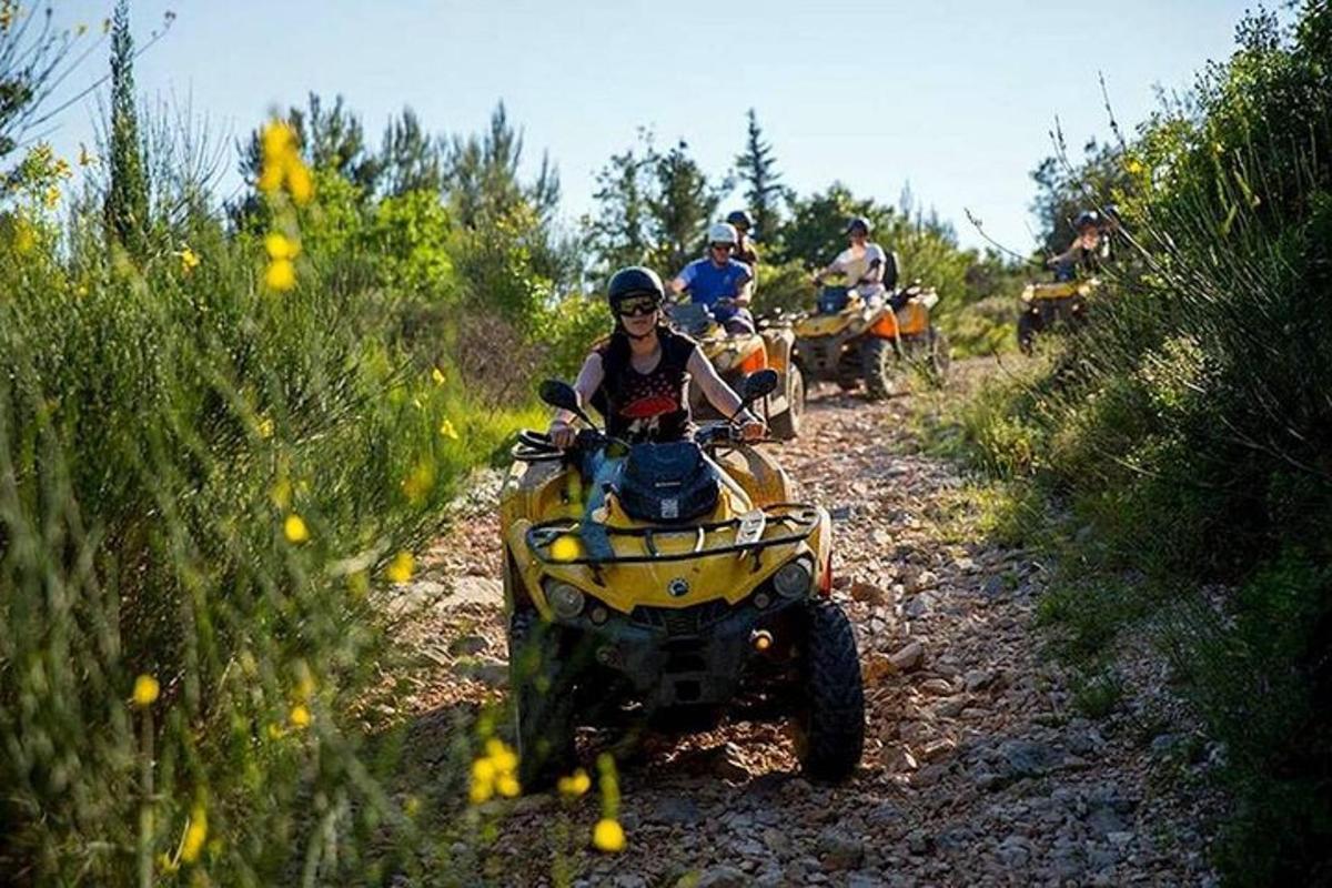 un grup de oameni care călătoresc cu ATV-uri pe un drum de pământ