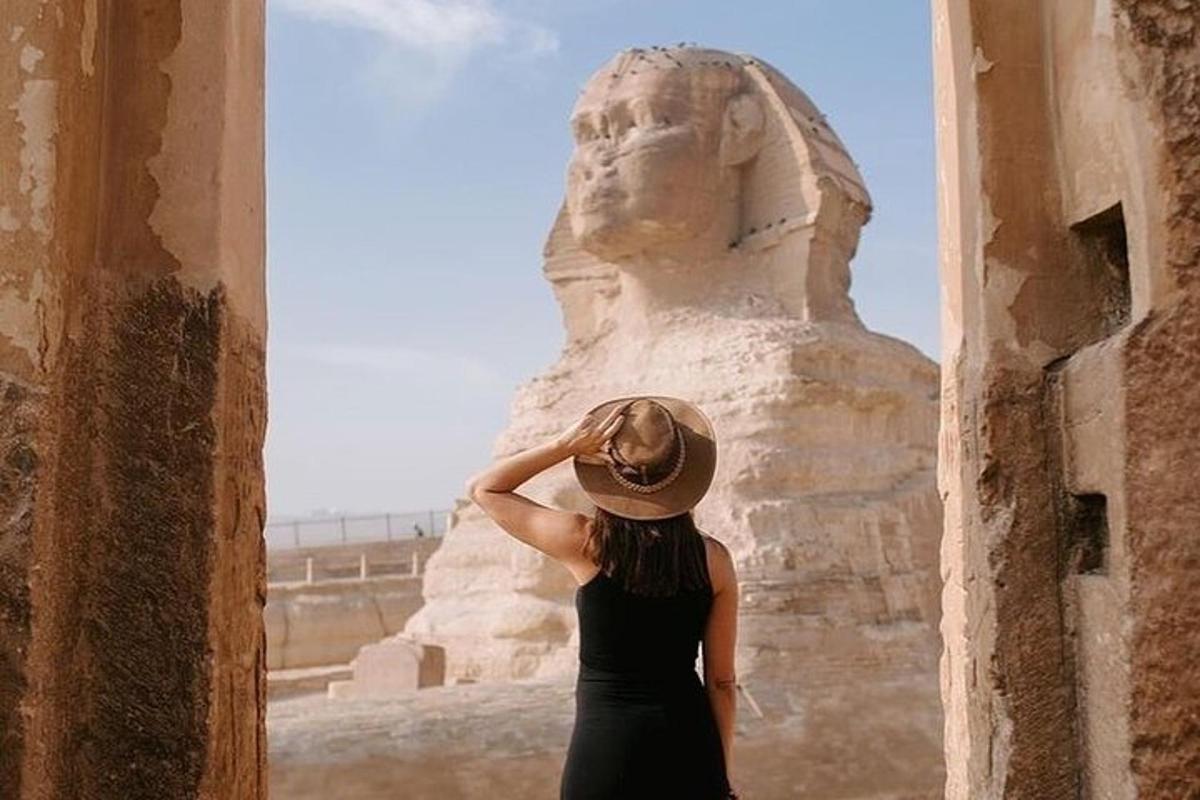 o femeie cu pălărie stând lângă o statuie