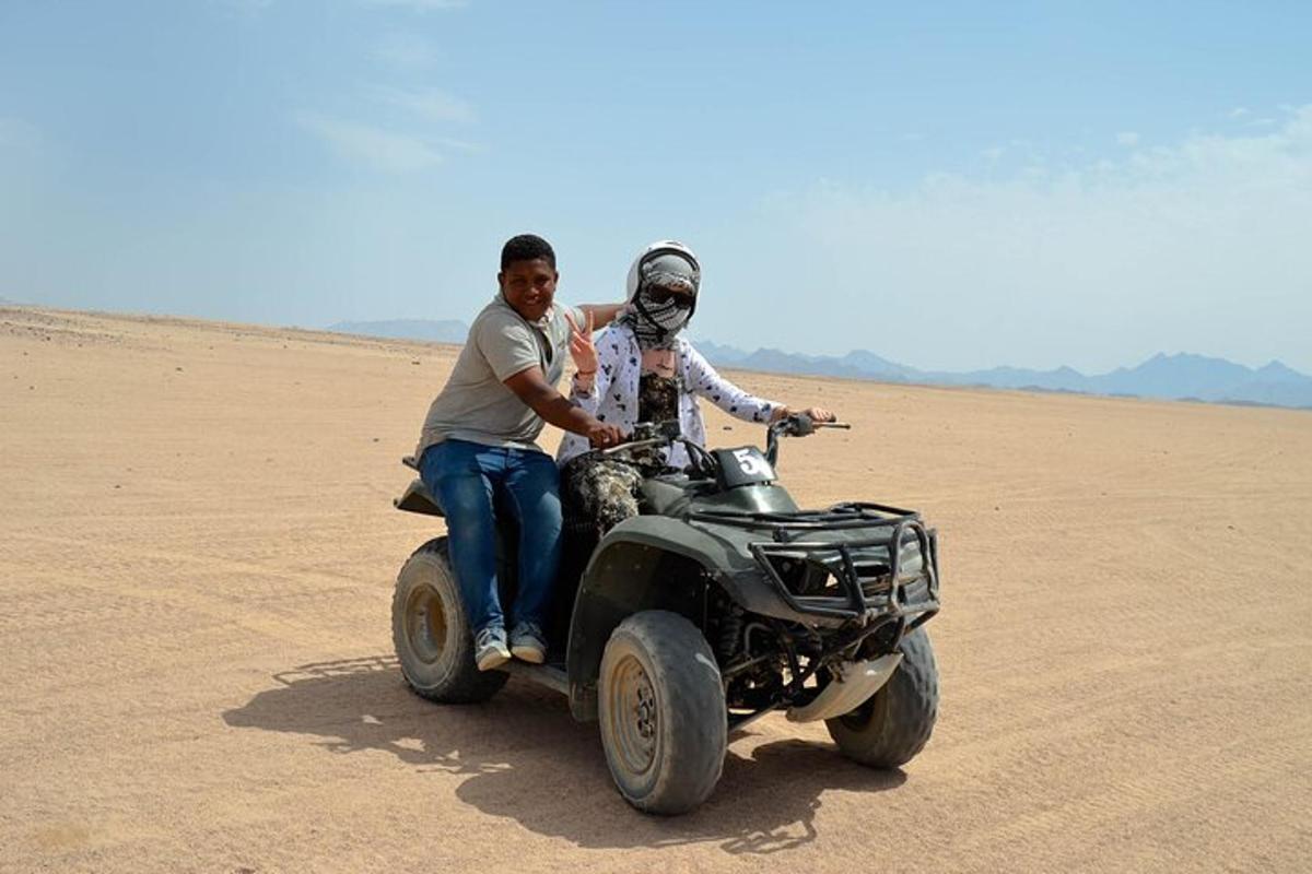 due persone a bordo di un veicolo a quattro ruote nel deserto