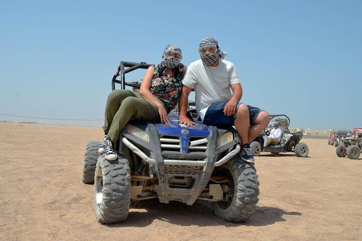 two people sitting on a four wheeler in the desert