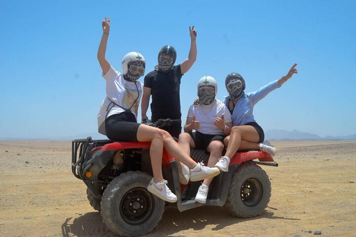 quattro persone sedute sul retro di un quad nel deserto