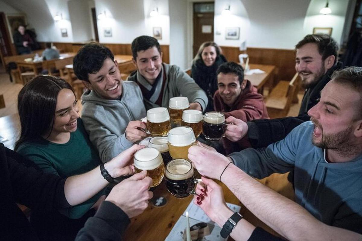 un grup de persones assegudes al voltant d'una taula bevent cervesa