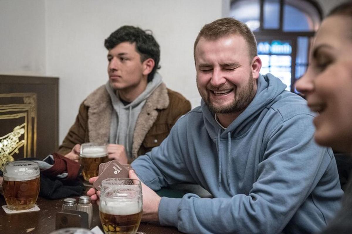 skupina mužů sedících u stolu a pijících pivo