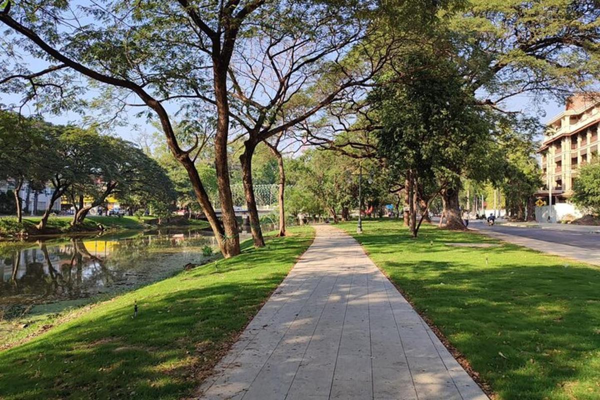 a walking path in a park with trees and water