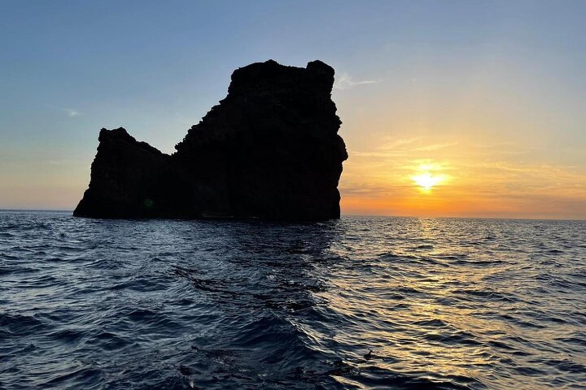 a rock formation in the ocean at sunset
