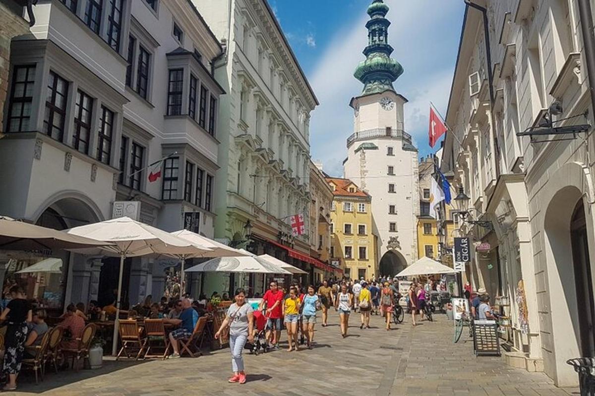 skupina lidí jdoucích po ulici s věží