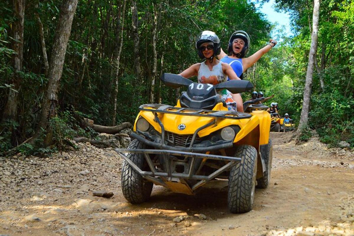 two people riding on a four wheeler on a dirt road