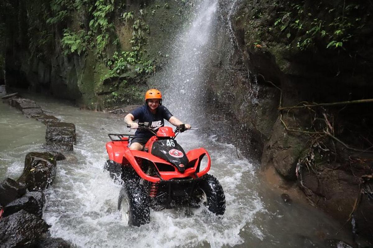 a man riding a four wheeler through a waterfall