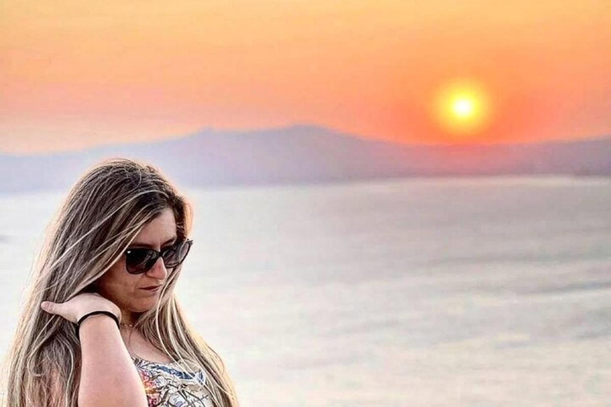 ženska s sončnimi očali stoji pred sončnim zahodom