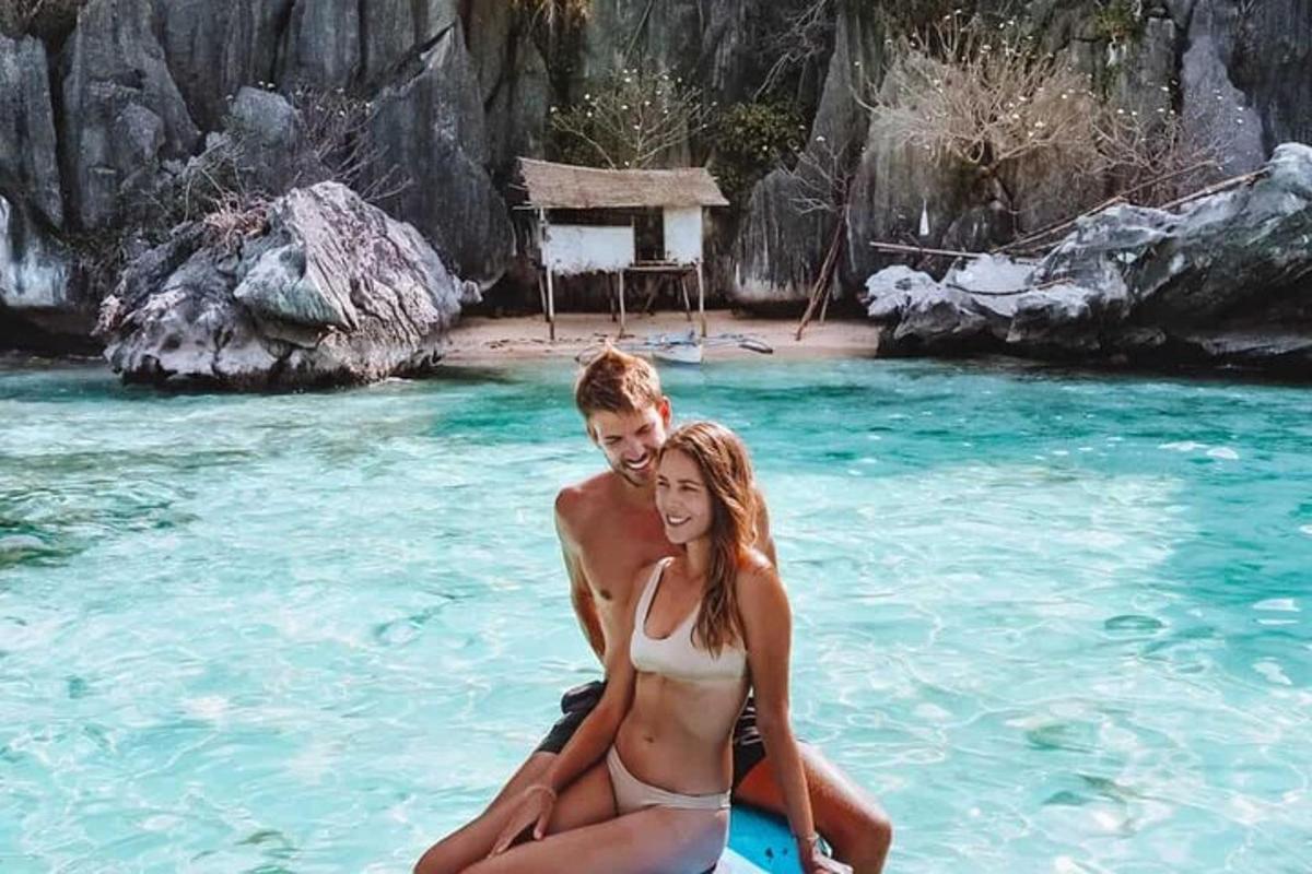 a man and a woman sitting on a surfboard in the water