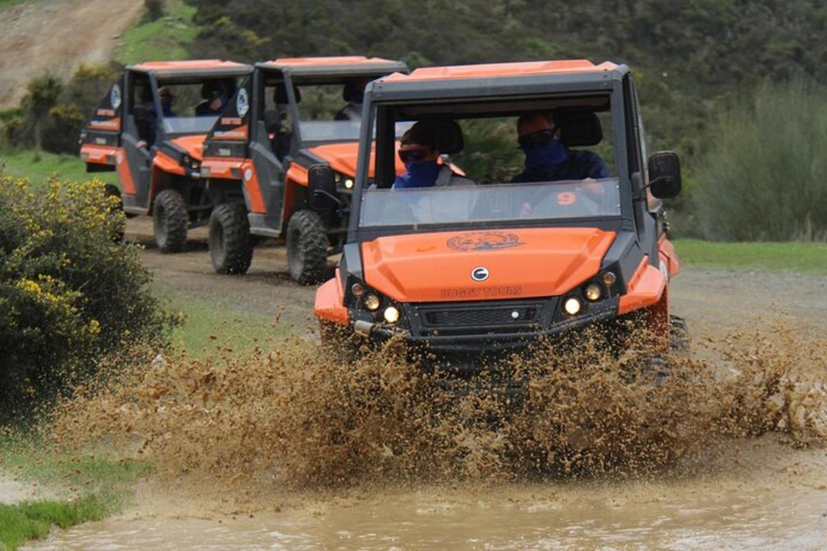 Un jeep naranja circulando por un campo embarrado
