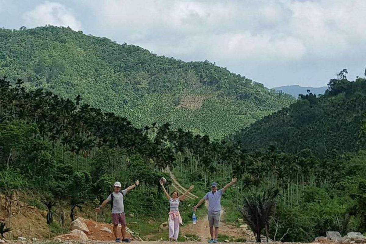 three people standing on a mountain with their arms up