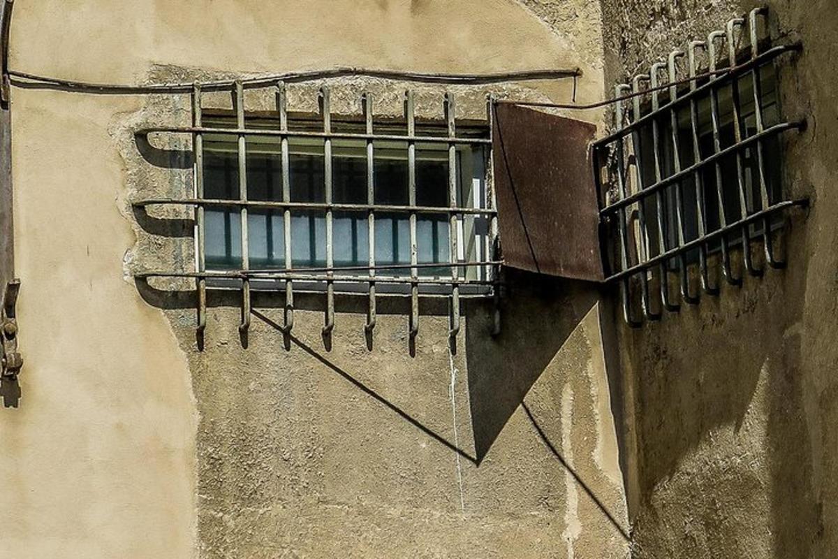uma janela com grades na lateral de um prédio