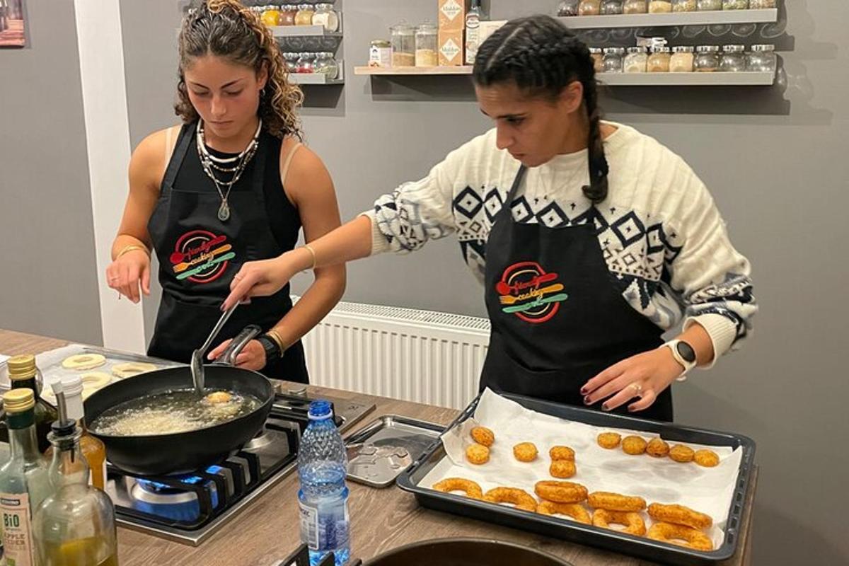 two women in a kitchen preparing doughnuts in a pan