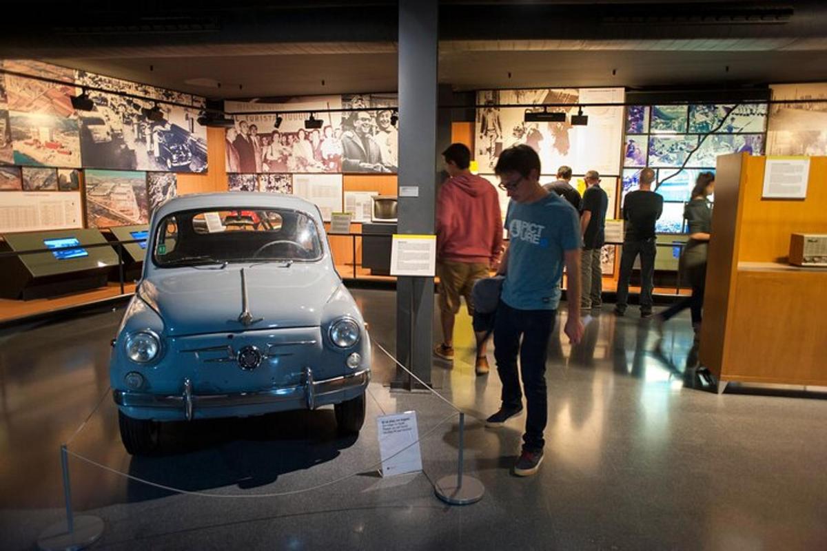 a group of people looking at a small car on display
