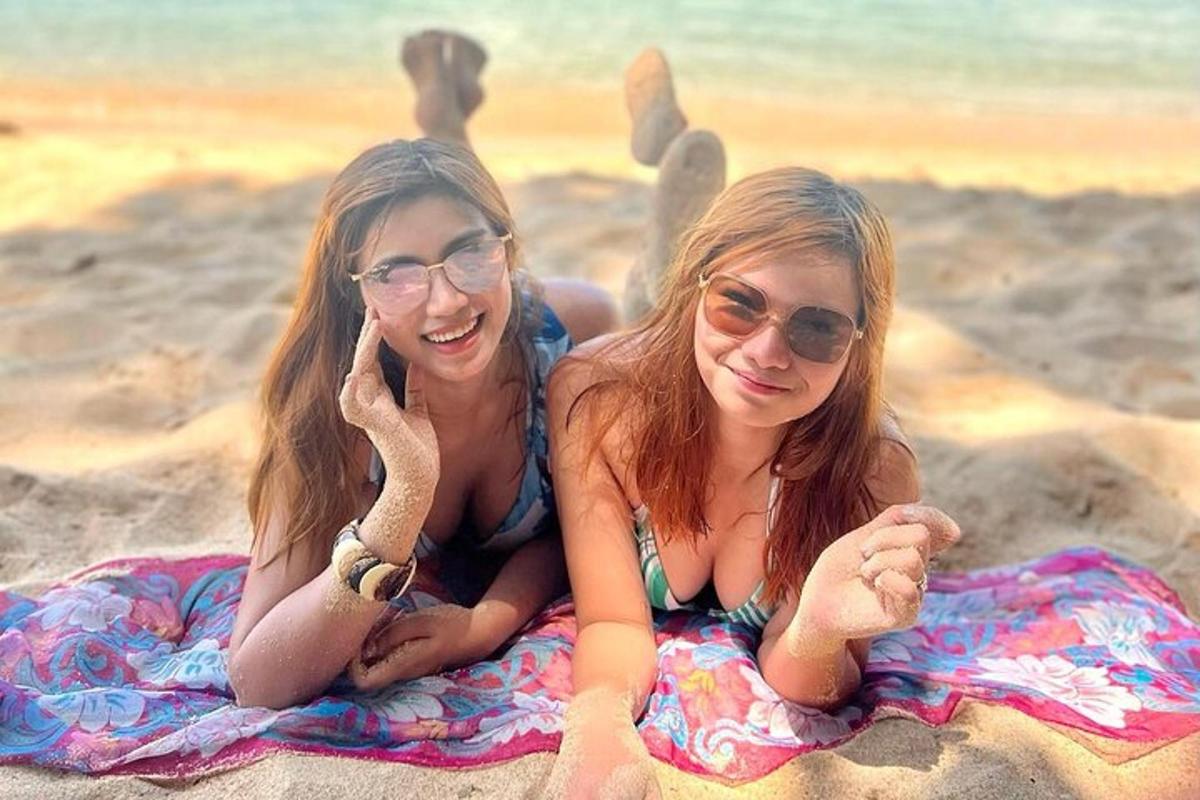 two girls laying on a towel on the beach