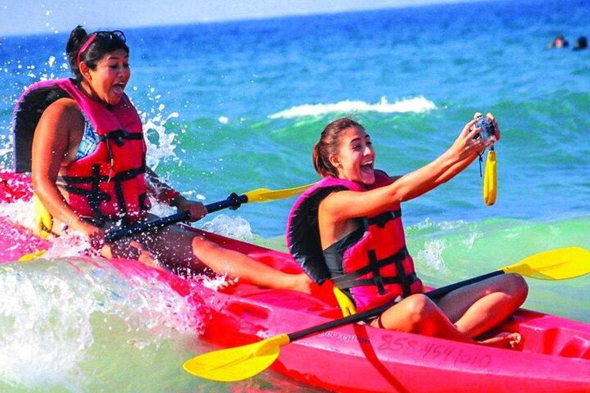 two women riding on a red kayak in the ocean