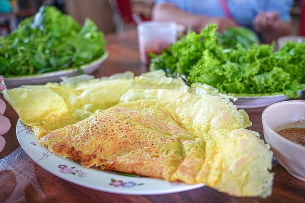a table topped with plates of food and greens