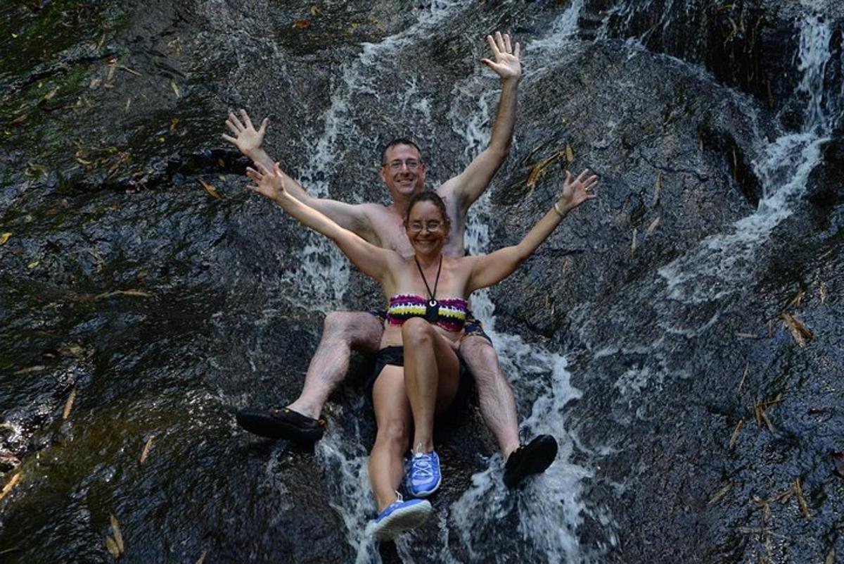a man and a woman sitting on a rock in a waterfall