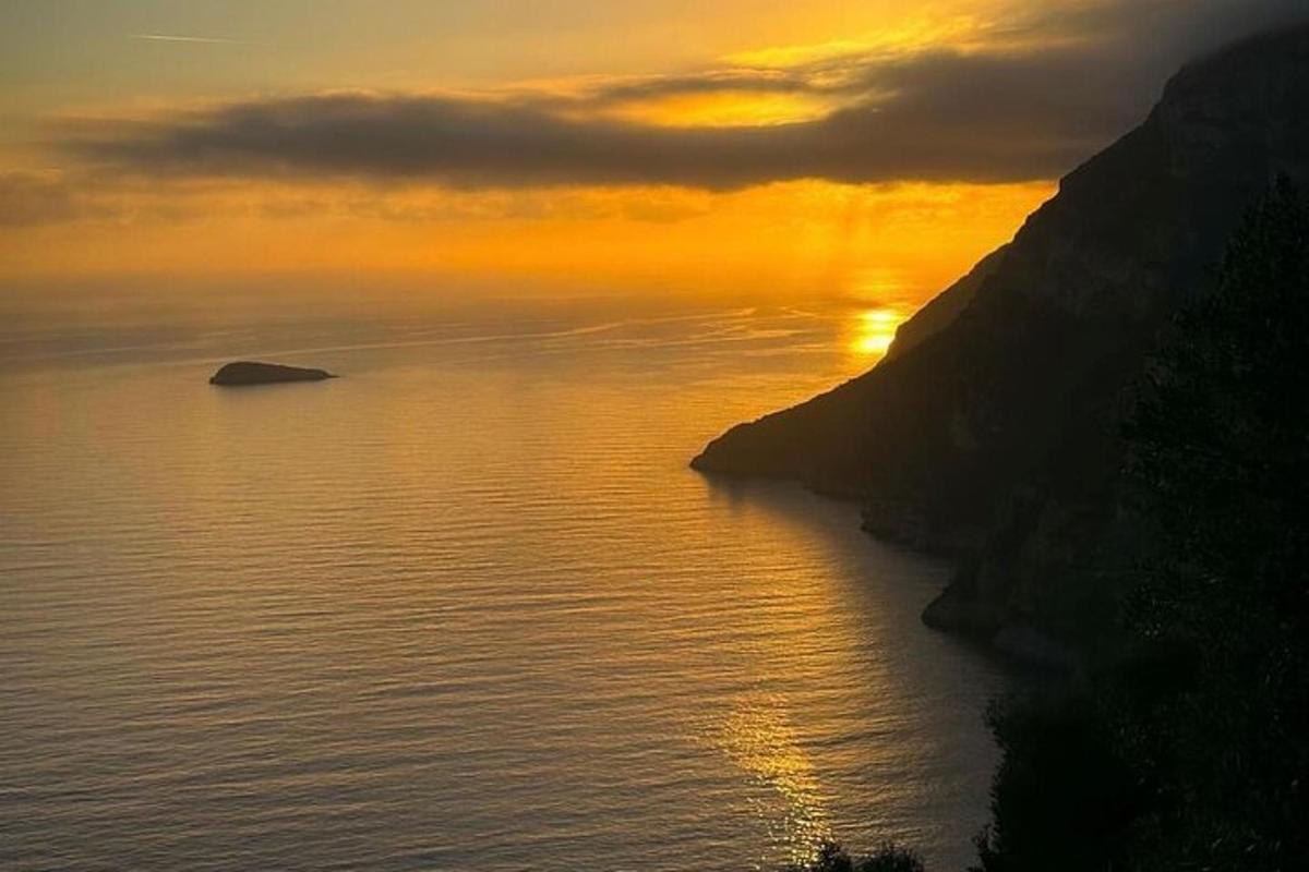 ένα ηλιοβασίλεμα πάνω από ένα υδάτινο σώμα με ένα βουνό