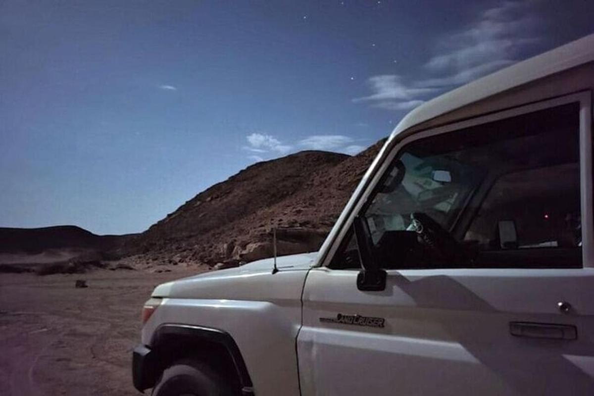 sebuah trak putih diletakkan di padang pasir dengan gunung