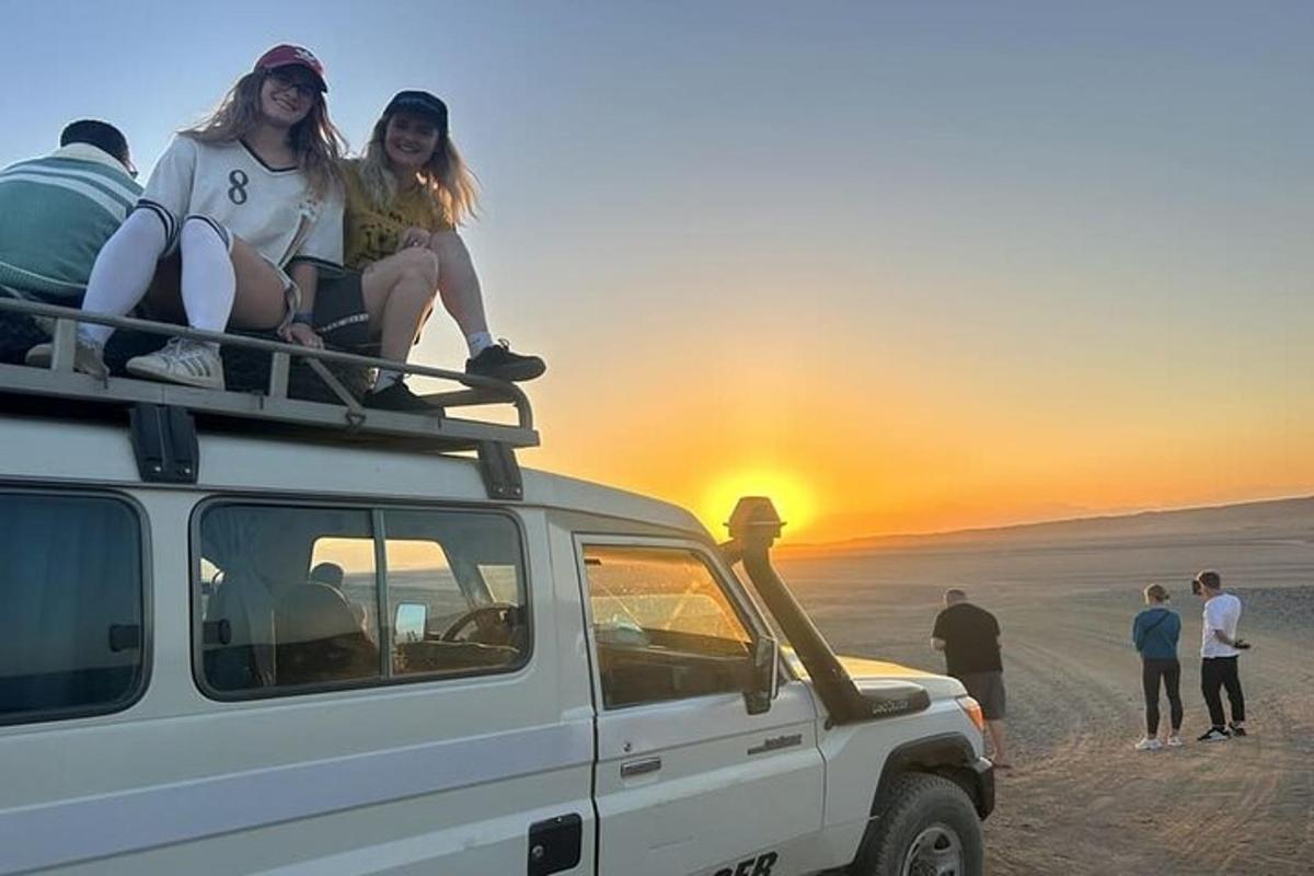 dua gadis duduk di atas bumbung kenderaan di padang pasir