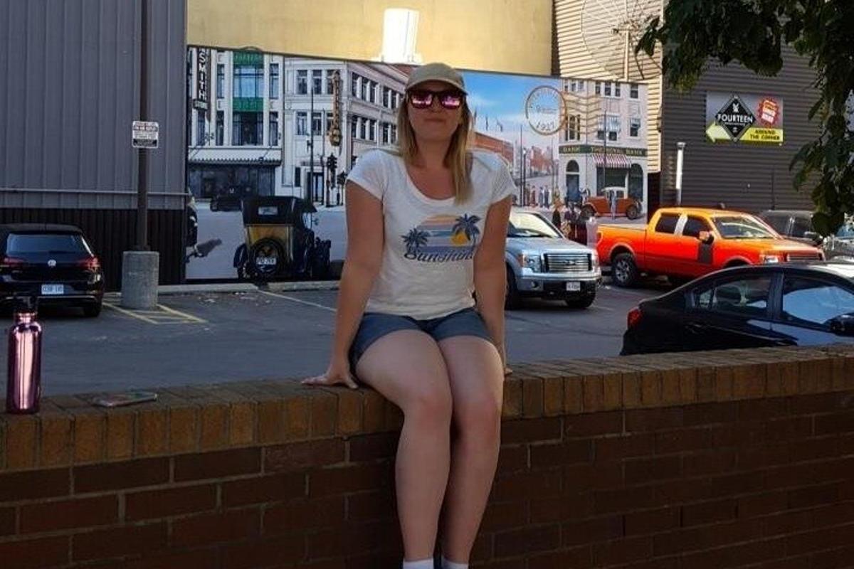 a woman is sitting on a brick wall