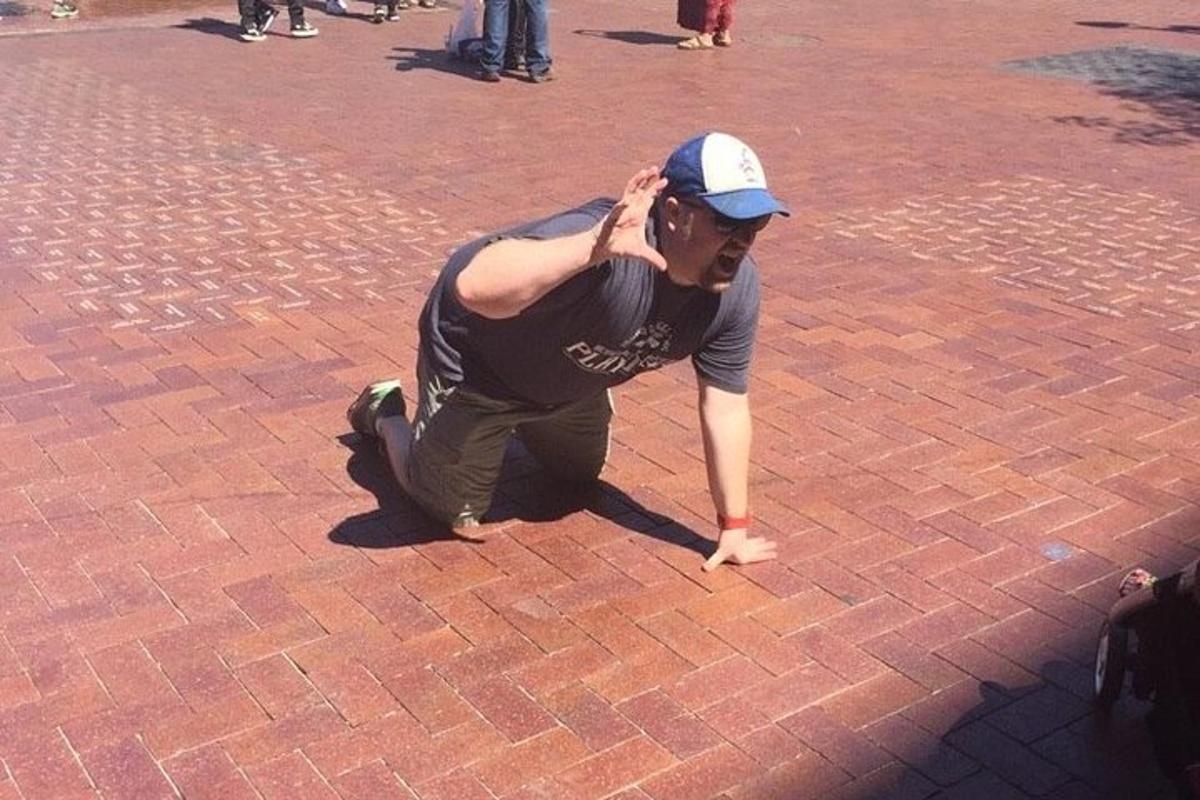 a man kneeling on the ground on a brick street