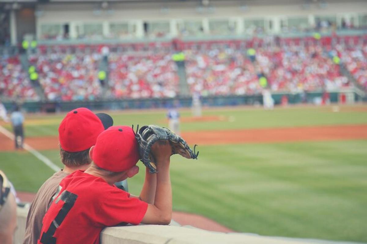 two boys sitting on a ledge watching a baseball game