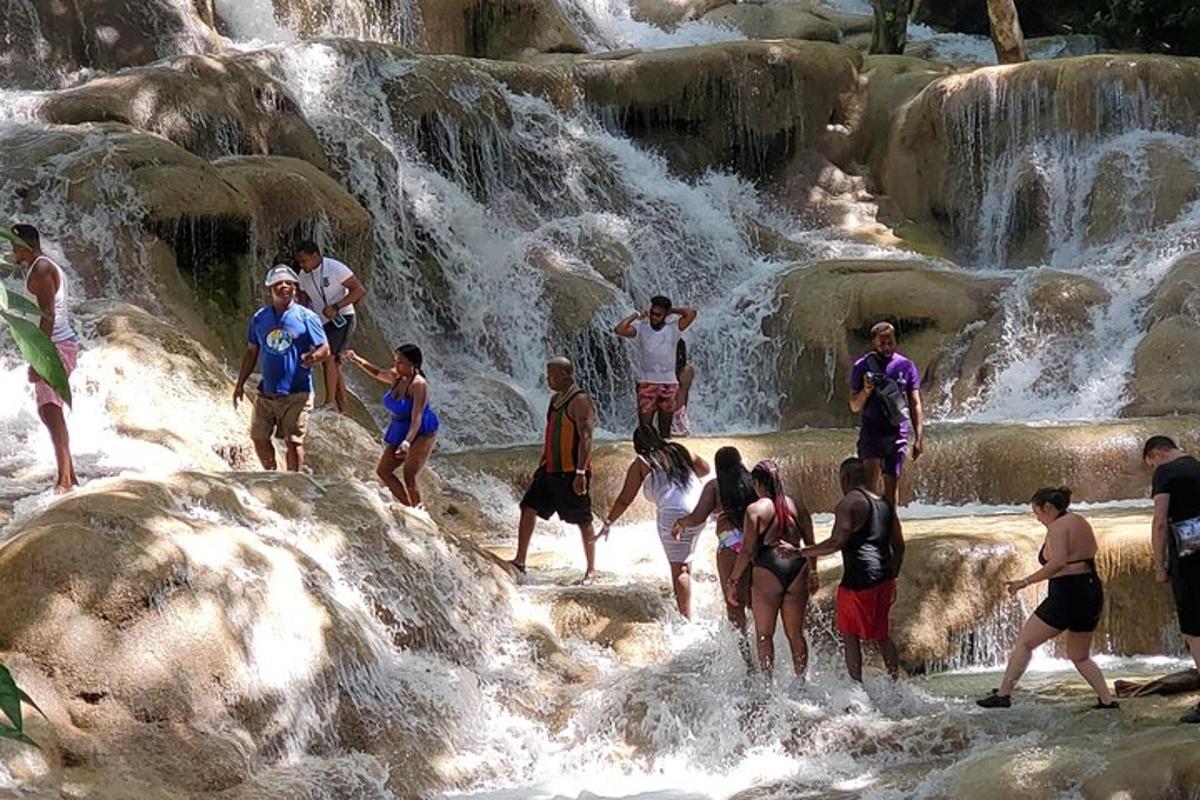 sekumpulan orang berdiri di dalam air terjun