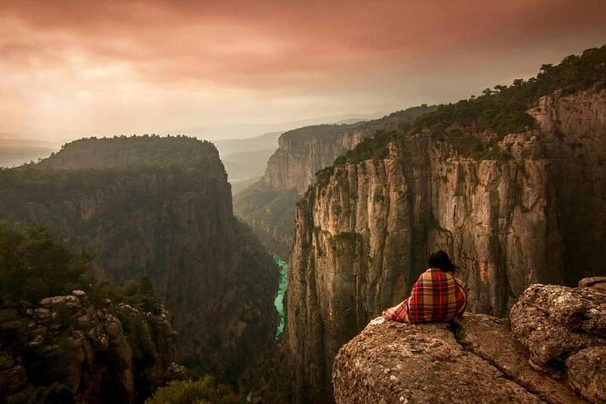 una persona seduta su una roccia che guarda verso un canyon