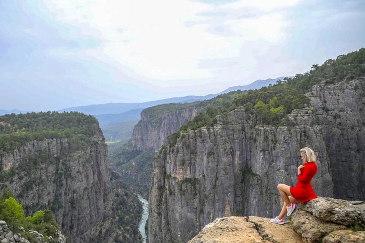 una donna in un vestito rosso seduta in cima a una montagna