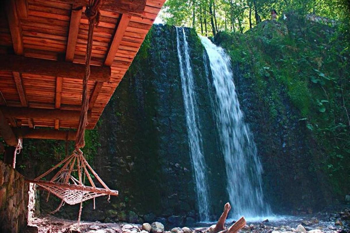 una cascata di fronte a una foresta con un edificio in legno