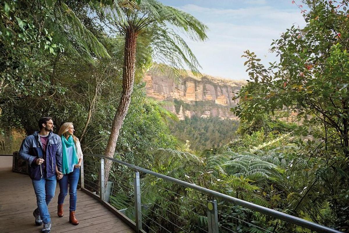 a man and woman walking on a walkway in the mountains