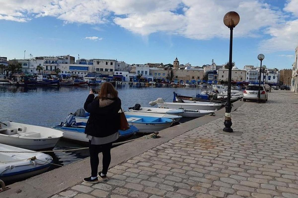 a woman taking a picture of boats in a harbor