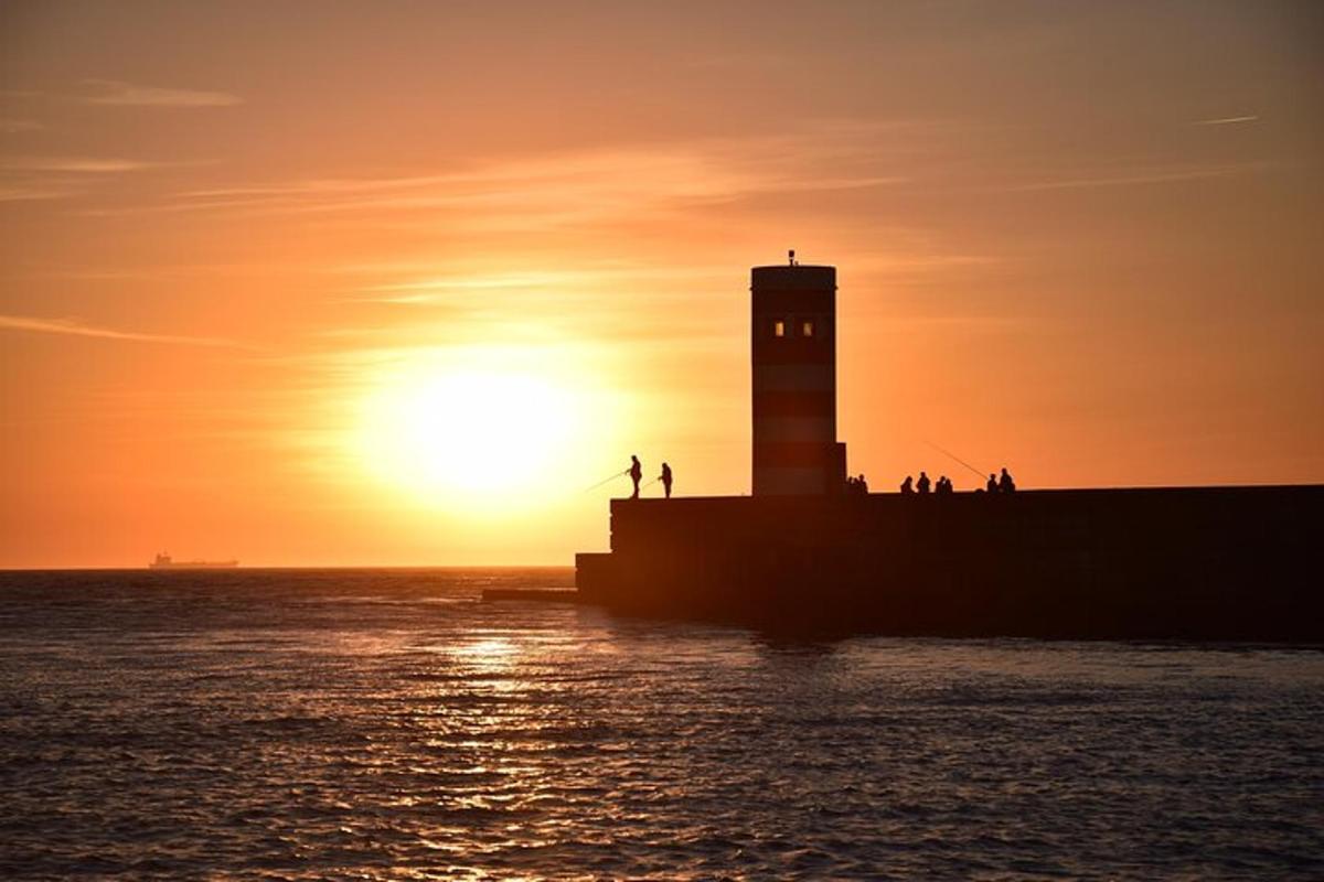 een vuurtoren bij zonsondergang met mensen die op een pier staan