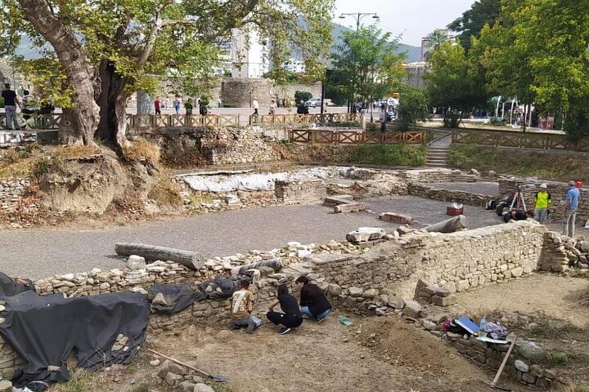 um grupo de pessoas sentadas em frente a um muro de pedra