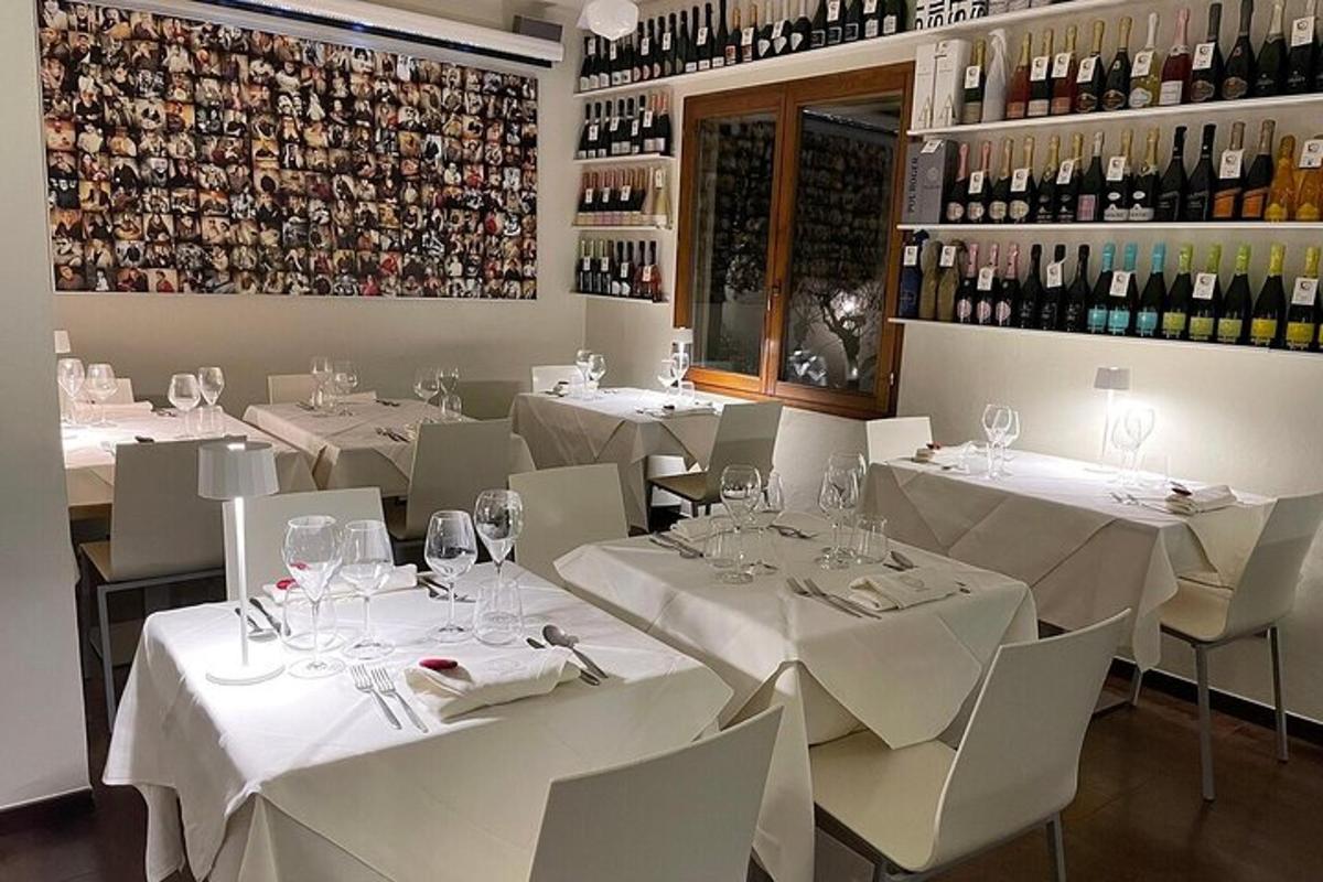 restaurace s bílými stoly a židlemi a lahvemi vína