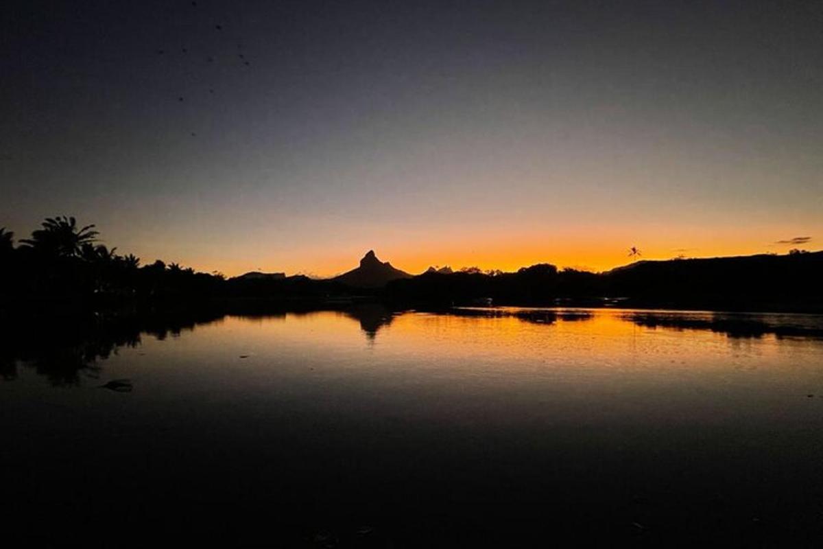 matahari terbenam di atas tasik dengan latar belakang gunung