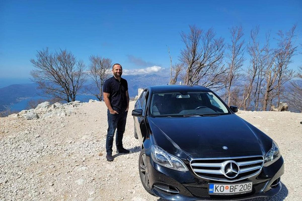 muž stojící vedle černého auta na kopci
