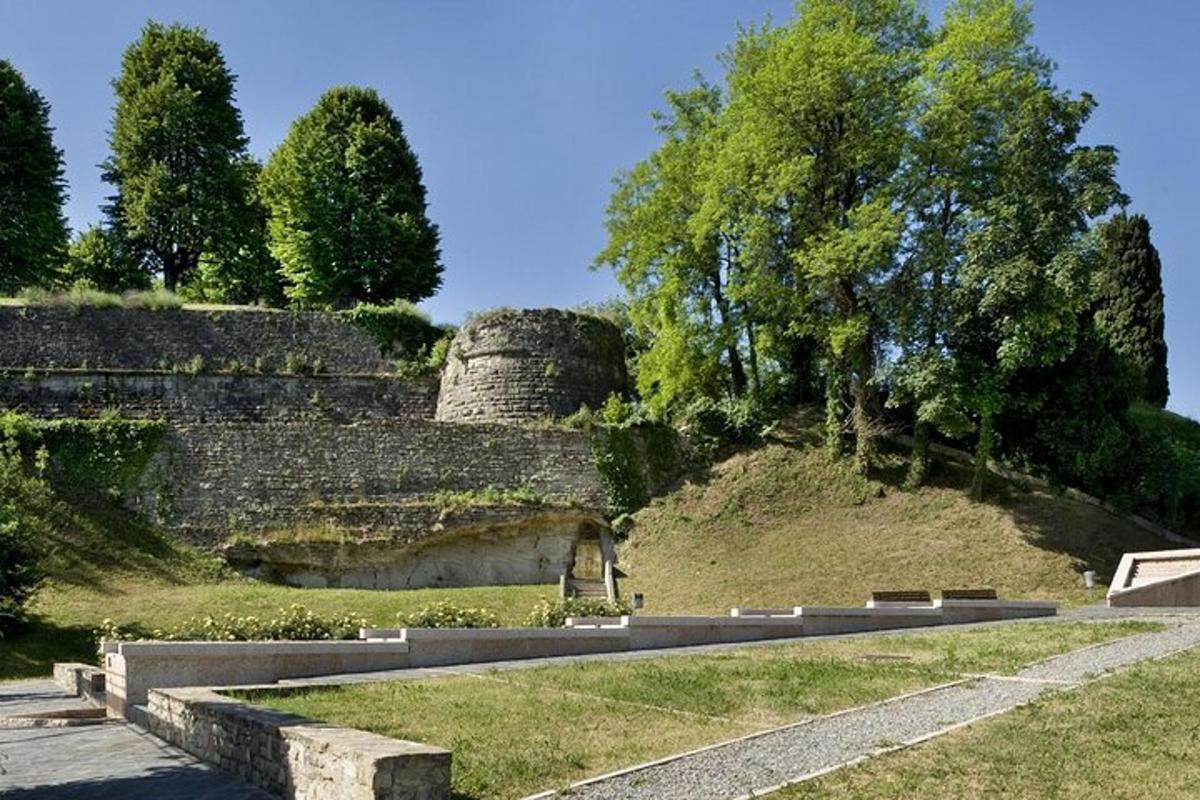a road in front of a stone wall with trees