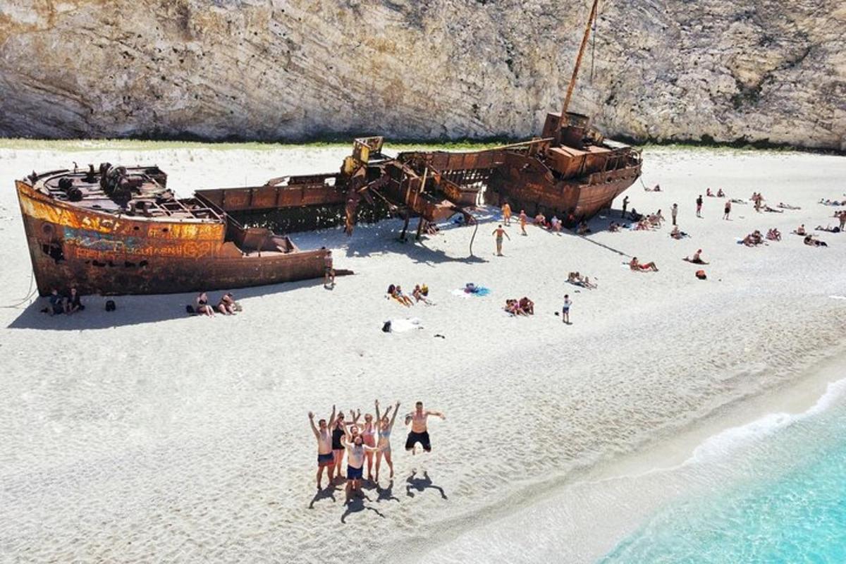 un grup de oameni pe o plajă lângă o navă veche